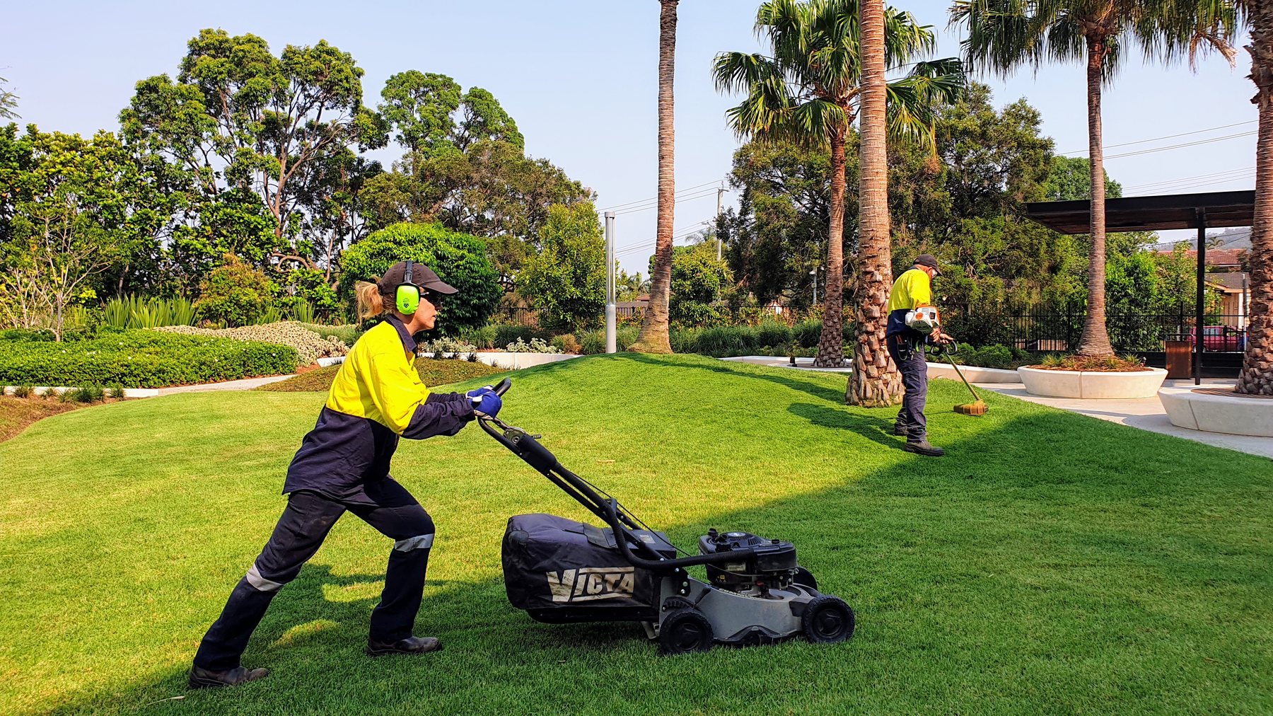 Garden Square — Grolife crew mowing the manicured commercial lawn with palm trees behind